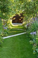 Chemin blanc traversant une pelouse en diagonale, avec des parterres d'arbres et de vivaces. Le jardin A Dogs Life, RHS Hampton Court Show