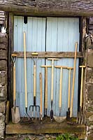Ligne d'outils de jardin De Wit contre une porte de grange en bois bleu
