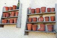 Étagères en bois fixées au mur empilées avec des pots en terre cuite