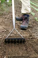 Jardinier utilisant un De Wit Sprake pour ratisser les sols
