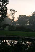 Ashton Court Park, Bristol, Royaume-Uni. Vue de la scène automnale à travers l'ancien étang, avec des arbres se découpant