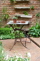 Chelsea Flower Show, 2009. Jardin 'Jacob's Ladder' (des. Jeff Hewitt) table et chaise simples et élégantes dans un petit jardin avec un pavage en briques