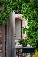 Jardin Rosalie Fiennes à Somerset avec portail en bois ouvert et table à manger extérieure
