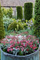Hanham Court Gardens, Bristol. Jardin du début de l'été avec des piliers topiaires et un grand pot métallique planté d'annuelles