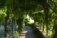 Villa La Foce, Toscane, Italie. Grand jardin avec couverture de boîte coupée topiaire et vue sur la campagne toscane, la pergola voûtée couverte de glycines