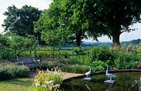 Jardin privé Sussex étang circulaire formel dans le coin de la campagne jardin oies sculpture banc en bois de chênes