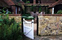 Cour inférieure Surrey design Transform Landscapes Courtyard patio garden avec mur de pierre et portail été septembre
