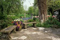 jardin privé Wiltshire patio à côté de la rivière pays jardin tulipes et pensées en pots bancs en pierre