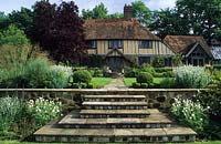 Shalford House Surrey design Sally Court marches en pierre menant à une pelouse surélevée avec vue sur maison