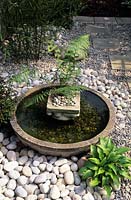 Un bol peu profond présente un style japonais dans un petit jardin de ville entouré de jolies pierres blanches et de paillis de galets