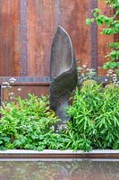 Sculpture dans le jardin Wedgwood contre un mur en métal rouillé. Conception: Jo Thompson. Commanditaire: Wedgwood