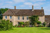 Vue sur maison d'époque anglaise avec étendue de pelouse.