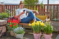 Femme regardant le téléphone tout en se relaxant sur le toit-terrasse du jardin.