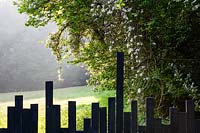 Clôture en bois peint en noir avec dessus irrégulier et vue sur le paysage au-delà