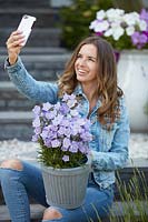 Femme prenant selfie en plein air avec pot de Campanula - campanules