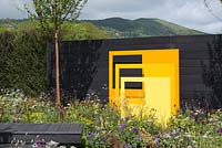 Panneaux sculpturaux en acier jaune avec fond de clôture noire - 'Urban Oasis', RHS Malvern Spring Festival, 2018.