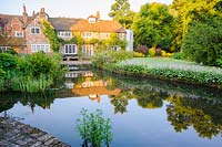 Les canaux d'eau autrefois utilisés pour conduire le moulin reflètent maintenant la maison et les jardins environnants. Dipley Mill, Hartley Wintney, Hants, Royaume-Uni.