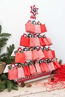 Sapin de Noël en palette de l'Avent décoré de sacs en papier remplis de cadeaux festifs dans un cadre festif moderne