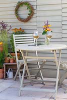 Table et chaises de jardin en bois peint avec verres à vin et composition florale