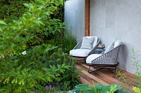 Le jardin Morgan Stanley pour le NSPCC - Deux fauteuils à côté du parterre de fleurs avec Euphorbia characias 'Black Pearl' - Sponsor: Morgan Stanley - RHS Chelsea Flower Show 2018