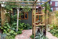 Petit jardin patio de Londres avec pergola centrale et bureau de jardin en arrière-plan.