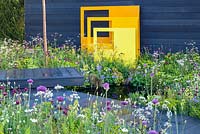 Panneaux sculpturaux en acier jaune avec fond de clôture noire dans une plantation de style pré - 'Urban Oasis', RHS Malvern Spring Festival 2018, parrainé par Graduate Gardeners Ltd.