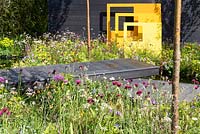 Panneaux sculpturaux en acier jaune avec terrasse en bois noir et plantation de style pré. 'Urban Oasis', RHS Malvern Spring Festival 2018.