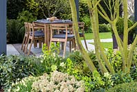 Vue sur la plantation mixte de la salle à manger avec table et chaises en bois - Jardin 'The Landform Spring' - Ascot Spring Garden Show, 2018.