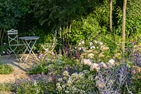 Rosa 'Wildeve', Centranthus et Salvia avec table et chaises. 'Le meilleur des deux mondes', RHS Hampton Flower Show 2018