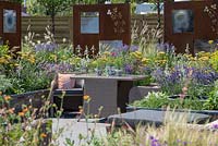 Mobilier de salle à manger en rotin extérieur entouré de plantes colorées - RNIB's Community Garden, RHS Hampton Court Palace Flower Show 2018