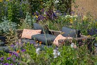 Canapé en rotin extérieur entouré d'un parterre de fleurs surélevé avec une plantation de plantes vivaces mixtes - RNIB's Community Garden, RHS Hampton Court Palace Flower Show 2018