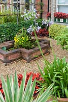 Jardin avant gravillonné avec plantes en pot et étang surélevé. Le jardin secret de Serles House, Dorset, UK.