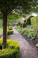 Découvre le parterre de fleurs dans le jardin d'été, avec des supports de noisetier prêts pour les plantes vivaces herbacées. Holker Hall, Grange over Sands, Cumbria, Royaume-Uni.