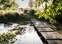 Terrasse en bois à travers l'étang. L'Oast House, Isfield, Sussex, UK