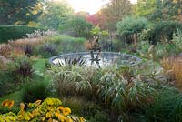 Jardin du dragon avec étang circulaire central avec sculpture de dragon. Knoll Gardens, nr Wimborne, Dorset, Royaume-Uni