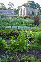 Potager clos de murs avec des rangées de légumes, des rangées de cloches et des plantes potagères boulonnées