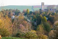 Église Saint-Michel et tous les anges, avec conifères, magnolias, rhododendrons et camélias. Jardins de Marwood Hill, Barnstaple, Devon, UK