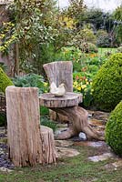 Table et chaises sculptées dans un tronc d'arbre, dans un jardin rempli de plantes