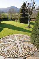 Un cercle décoratif en mosaïque d'ardoise et de galets s'étend du chemin supérieur dans la pelouse. Plas Brondanw, Penrhyndeudraeth, Gwynedd, Pays de Galles