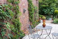 Un patio fermé avec une petite fontaine entre les nectarines et les figues entraînées par un ventilateur.