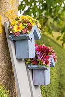 Paire de nichoirs en bois aux toits ornés de fleurs montés sur des planches peintes