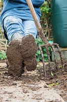 Jardinier au repos, portant des bottes boueuses après avoir creusé le jardin.