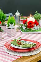 Cadre de table festif rouge, blanc et vert, avec vue sur la pièce maîtresse de l'arrangement des bougies.