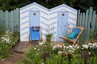 Cabines de plage bleues et blanches et chaises en bois bordées de plantations côtières bleues et blanches. Southend Council 'By The Sea' garden at RHS Hampton Court Flower Show, Londres, 2017.