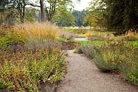 Un chemin de gravier mène à travers des parterres de graminées vivaces et de têtes de semences conçus par Piet Oudolf - Trentham Gardens, Staffordshire, Royaume-Uni.