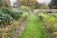 Sentier d'herbe à travers le jardin clos, avec des rangées de passages de pommes fructifères. Gravetye Manor, Sussex, Royaume-Uni.
