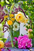 Arrangement floral d'été dans un vase en verre avec Rosa, Hortensia, Amaranthus, Zinnia, Dipsacus, Verbascum et Achillea.