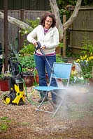 Nettoyage de meubles de jardin femme avec un nettoyeur haute pression.