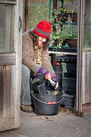 Femme ranger la serre et laver les pots en hiver.
