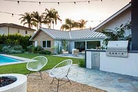 Vue sur le jardin avec des guirlandes lumineuses pour la piscine et le coin salon extérieur. Jardin conçu par Falling Waters Landscape, inc Ryan Prange, New Port Beach, Californie, USA.